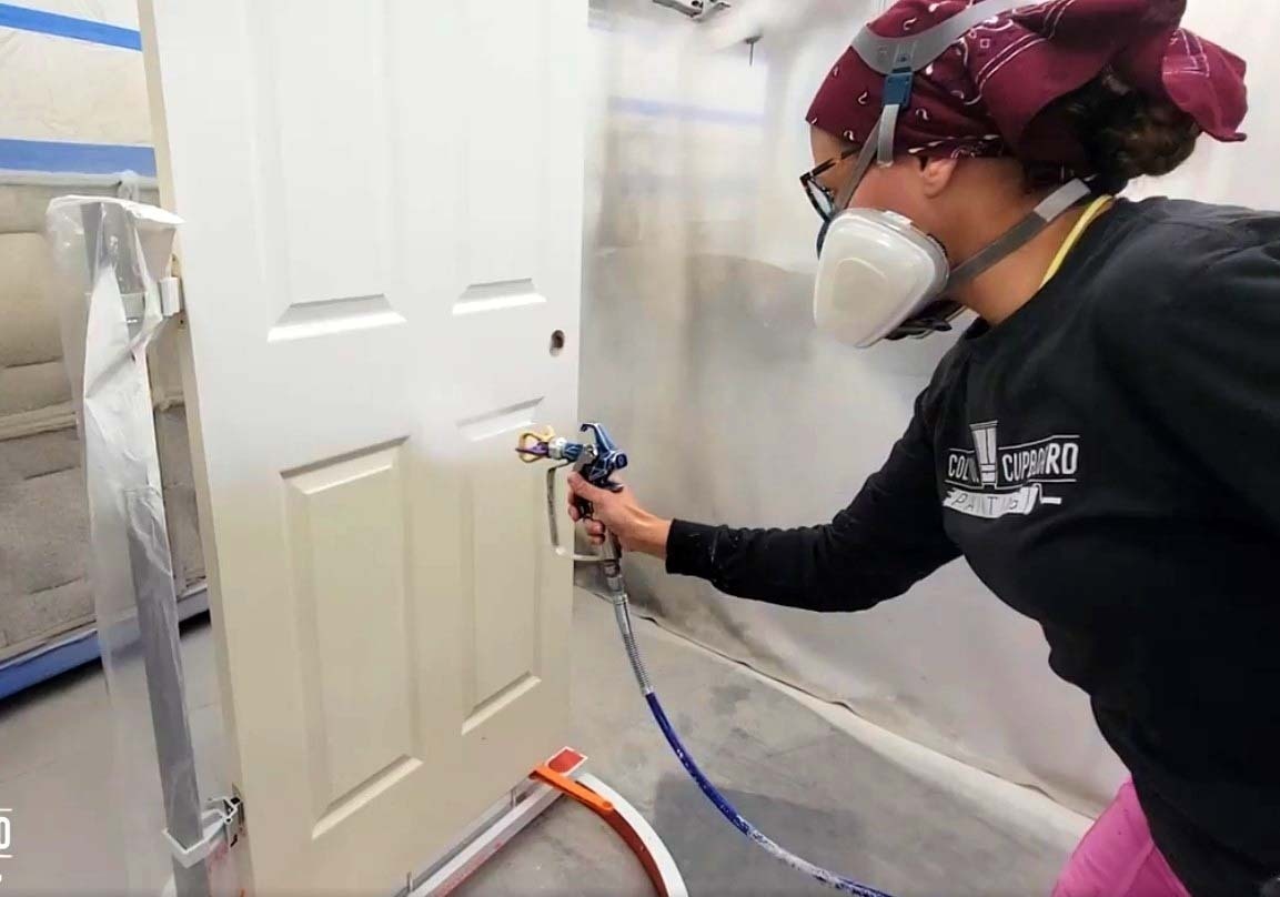 Worker spraying a door with a fresh coat of paint